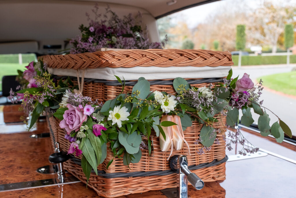 wicker casket with flowers in a hearse